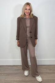 Woman wearing a brown blazer on top of a light brown hoodie with matching pants