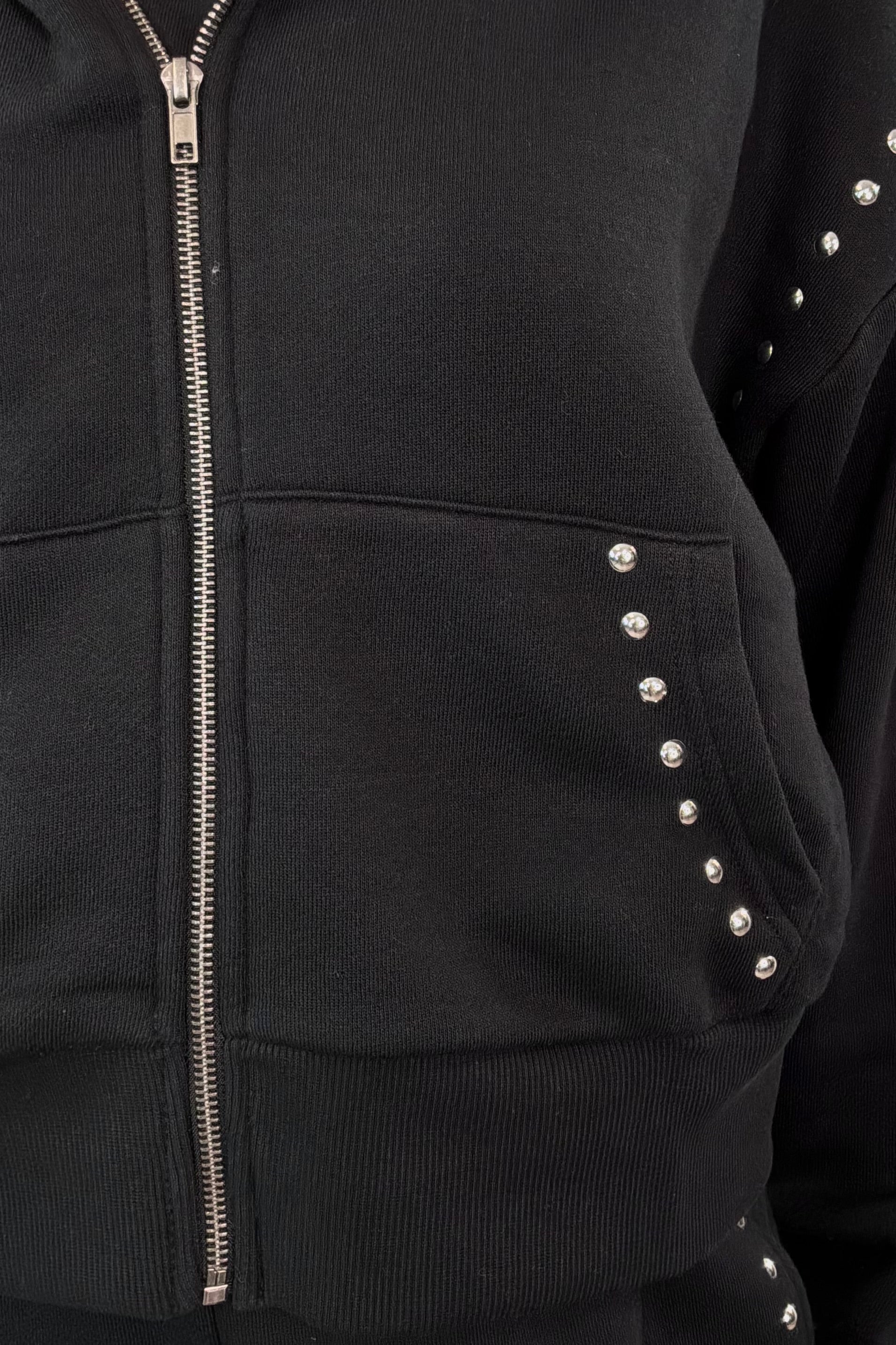 close-up of a black zip-up with studs along the seems