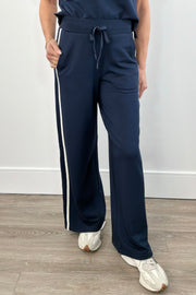 Woman wearing navy wide leg pants with drawstring waistband and contrast white side stripe
