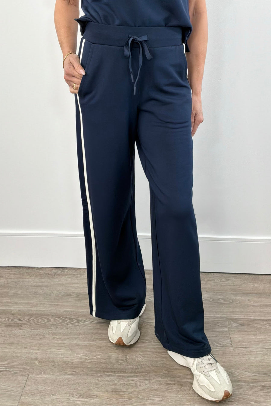 Woman wearing navy wide leg pants with drawstring waistband and contrast white side stripe
