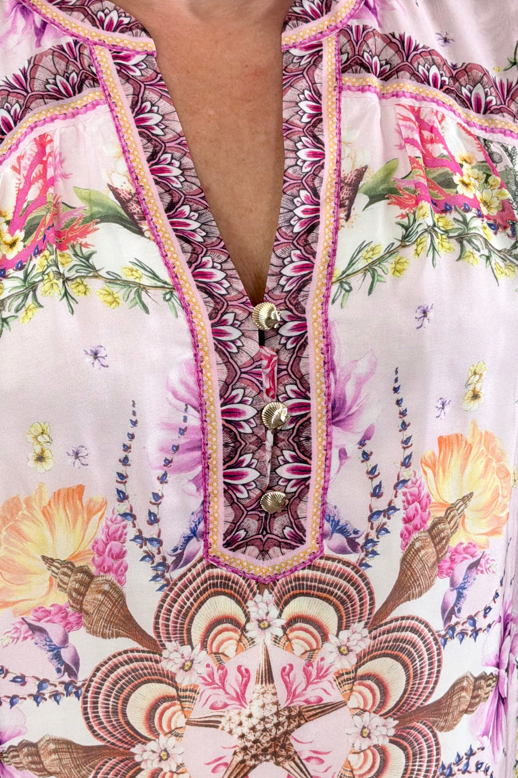Woman wearing a pink floral blouse with a detailed shell pattern and 3/4 sleeves 