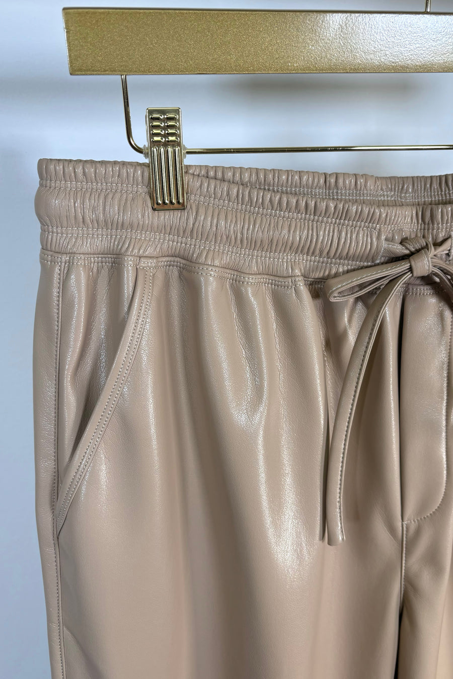 Close-up of the waist of a tan leather drawstring pants