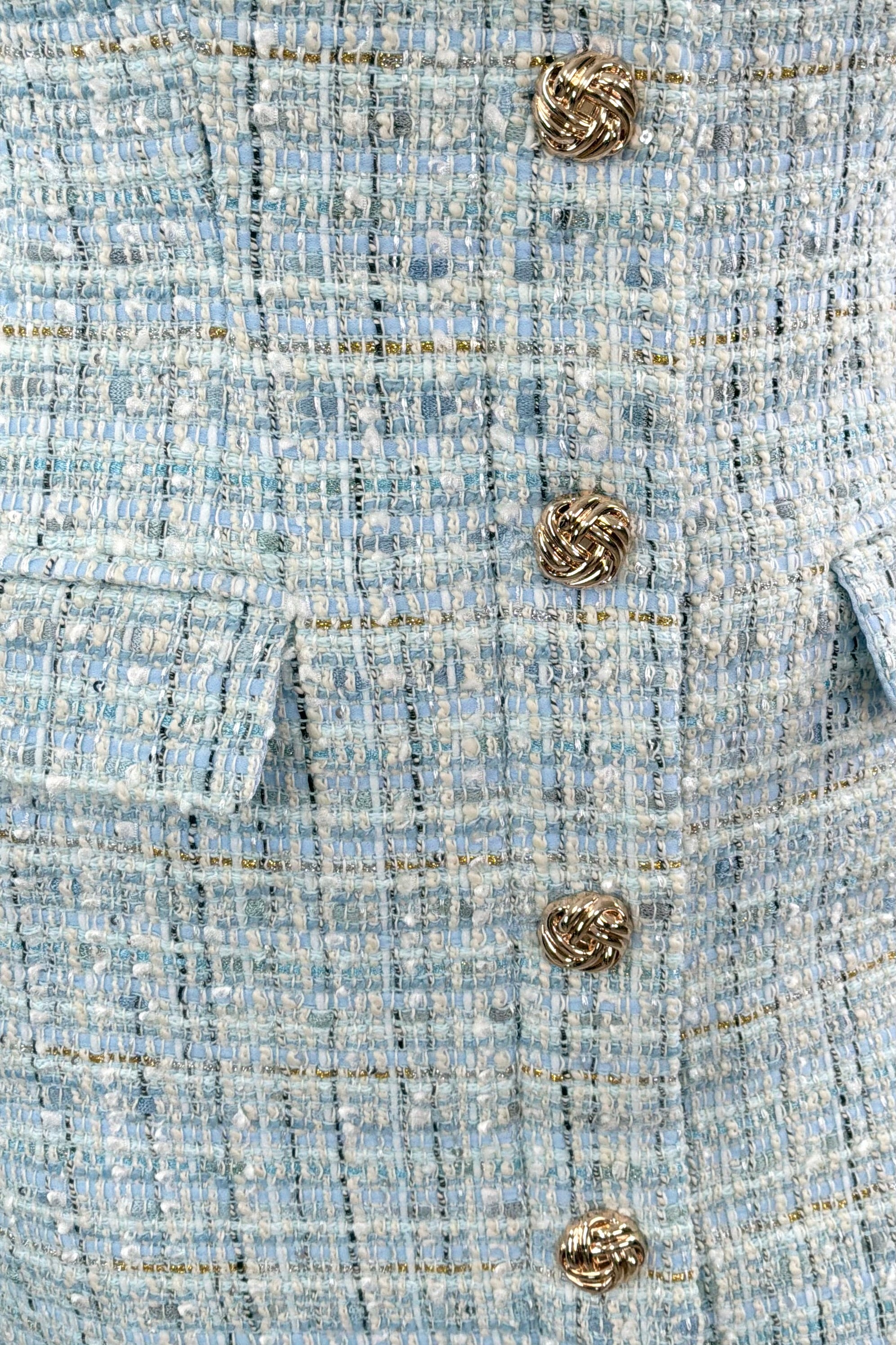 Close up of Woman wearing a aqua blue tweed dress with gold button details