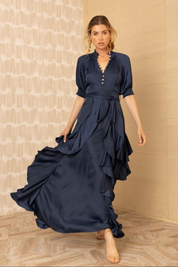 Front view of woman wearing a silk v-neck navy blue dress with ruffles