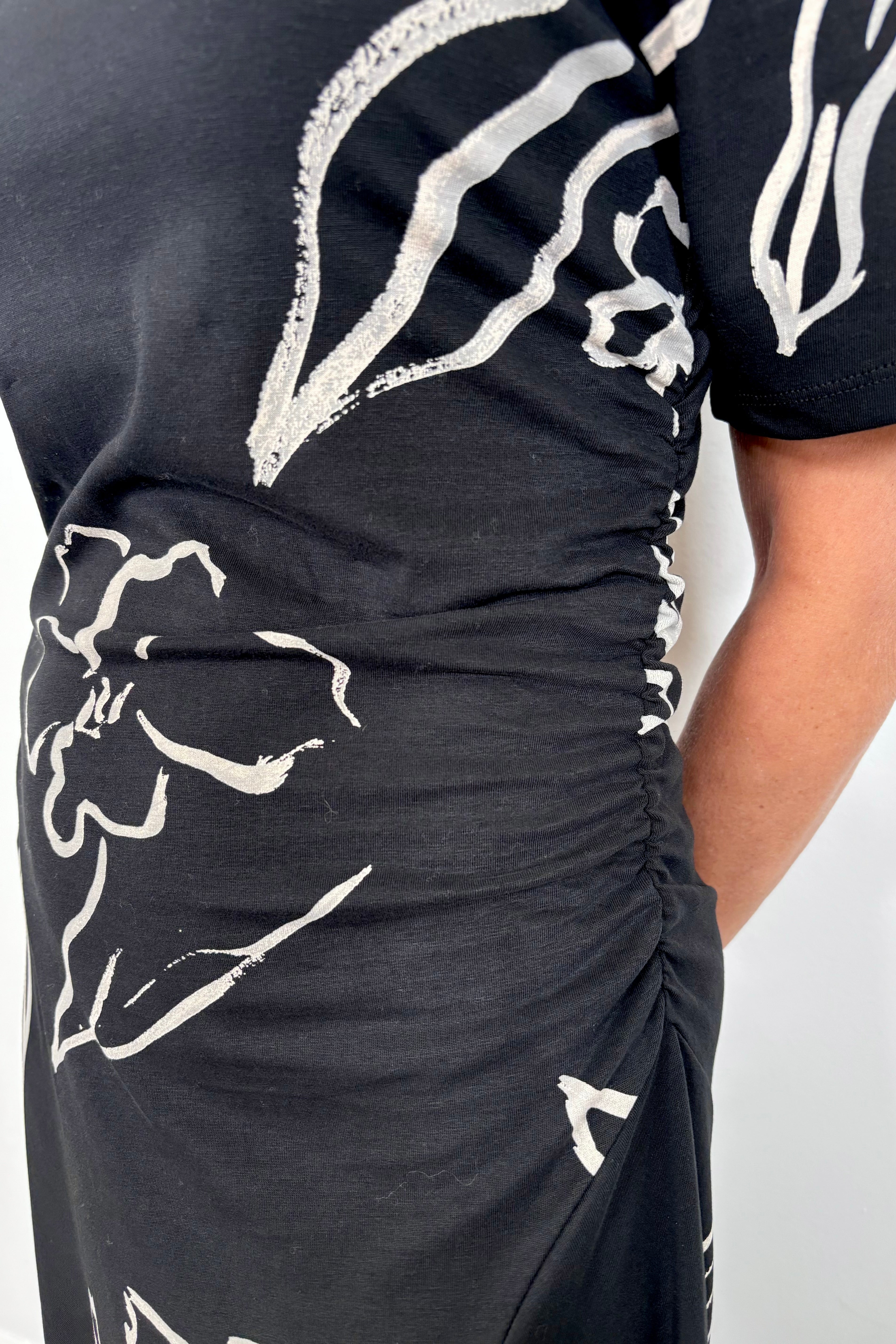 Black dress with white floral patterns on a plain background