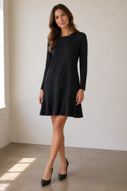 A woman modeling a black long-sleeve shift dress with a flared skirt