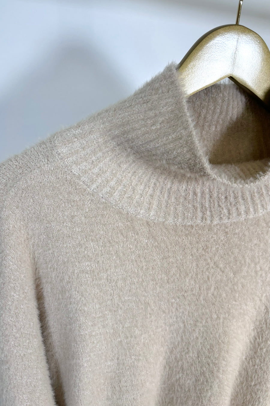 Close-up of the mock neck of a half sleeve hairy cream sweater