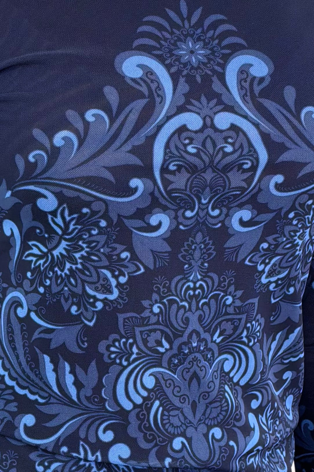 Close-up of a dark blue mesh top with intricate floral and paisley patterns.