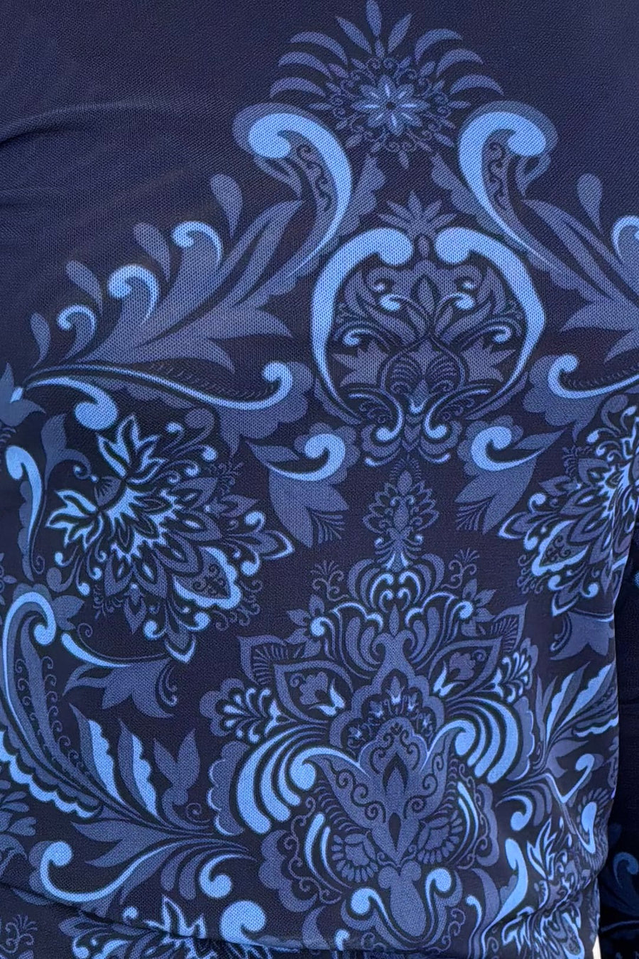 Close-up of a dark blue mesh top with intricate floral and paisley patterns.