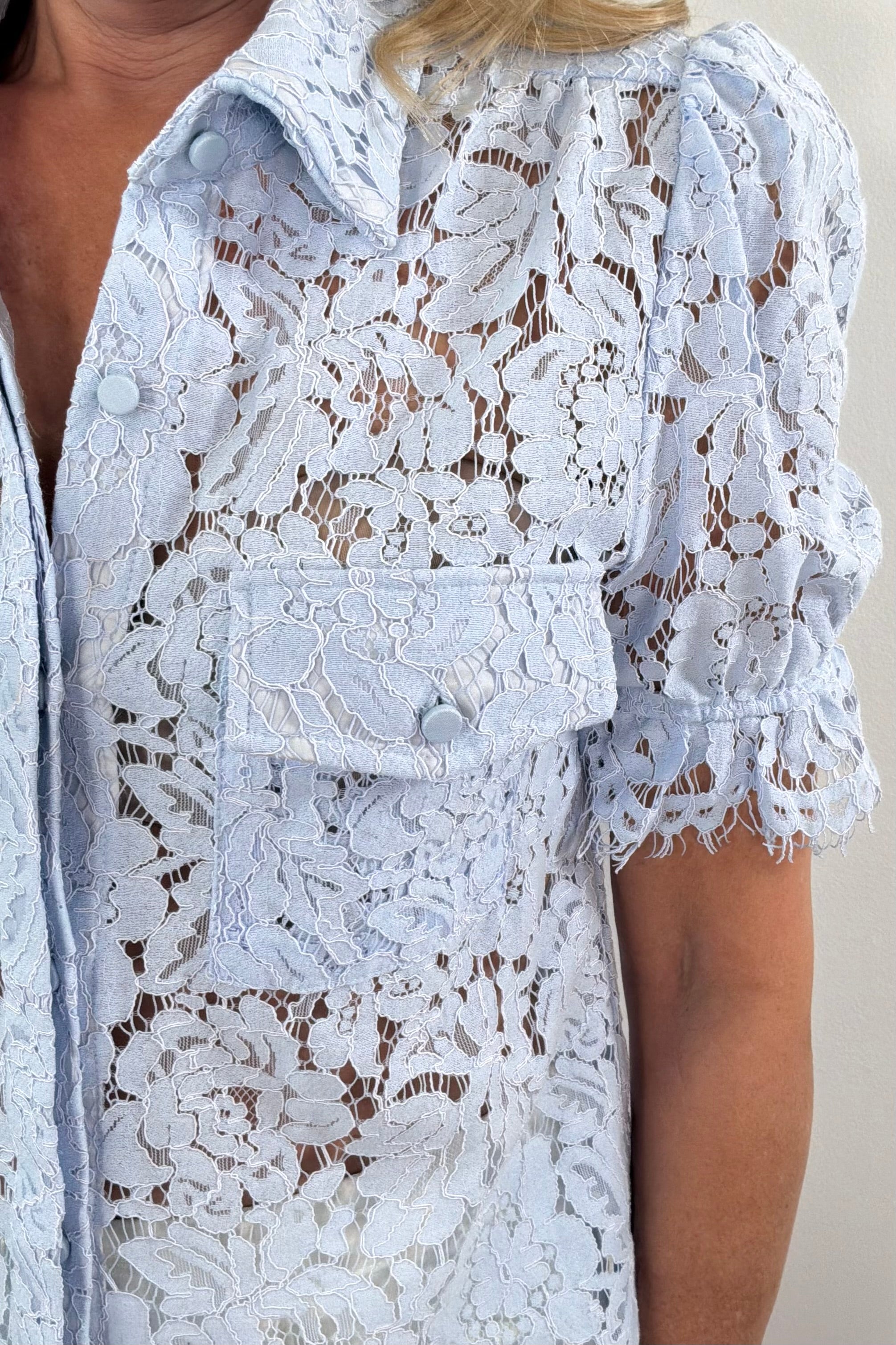 Close up of pocket detail on light blue lace button up shirt