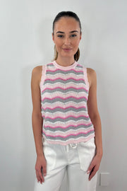 A woman wearing a knit vest with a zig zag stitch in a pink grey and white pattern