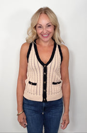 Woman wearing a beige knitted vest with black trim on a white background