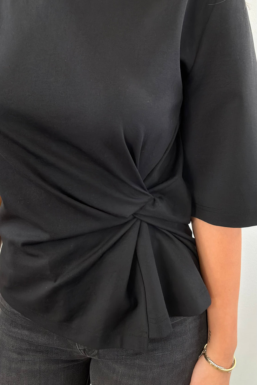 Woman wearing a black top with a knot detail
