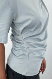Woman wearing a blue gray t-shirt with twist detail