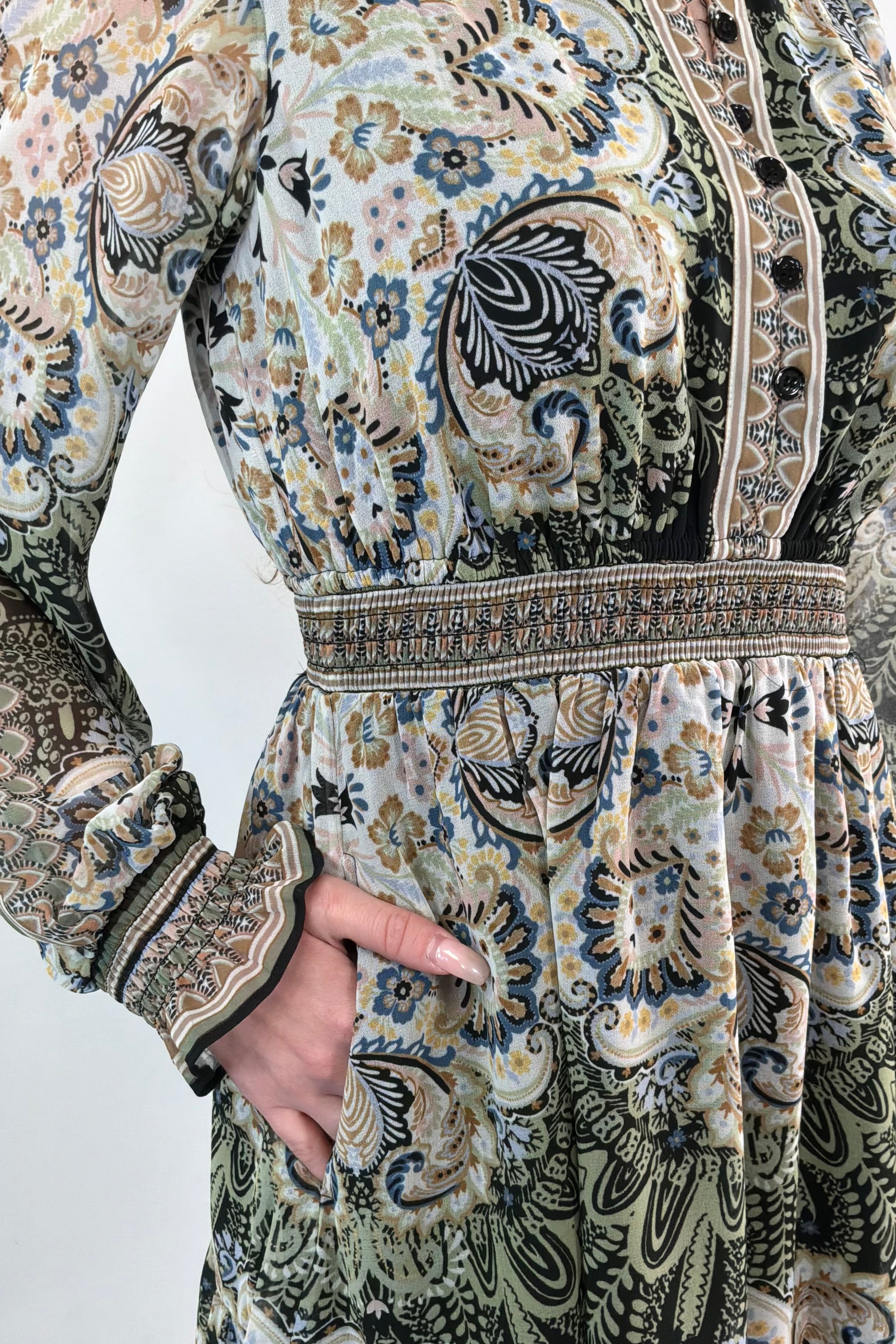 Close-up of an ivory, green and black short A-line long sleeve dress