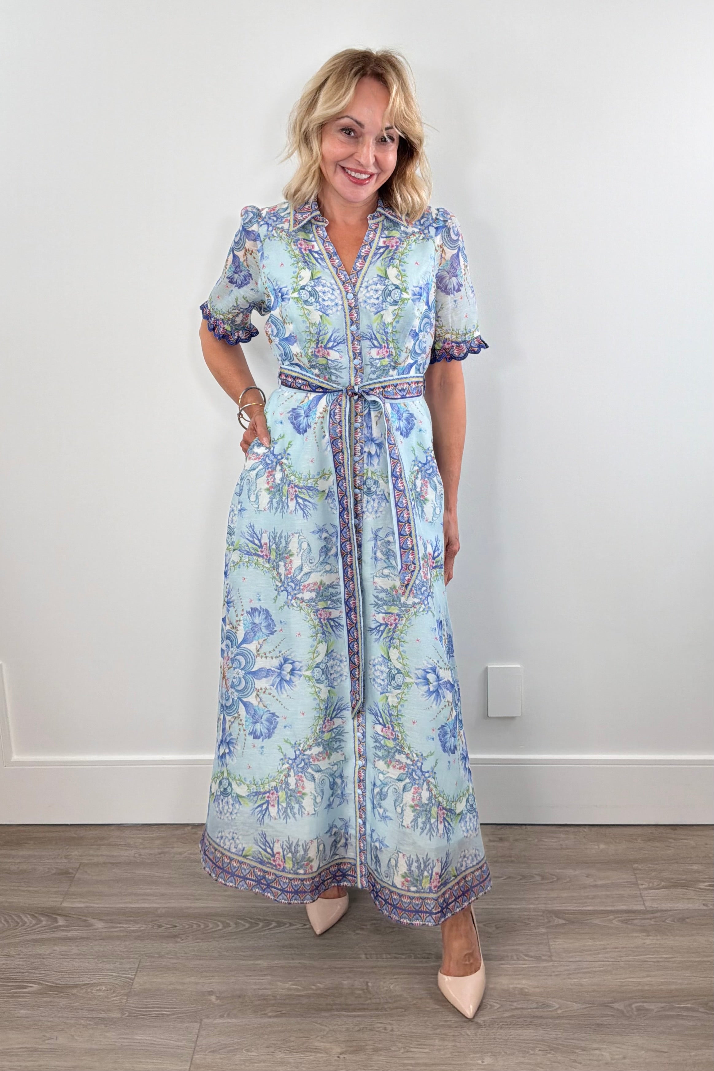 Woman wearing a long blue floral dress with detailed sleeves 