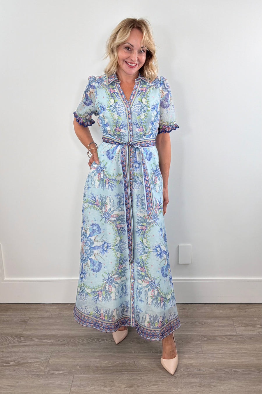 Woman wearing a long blue floral dress with detailed sleeves 