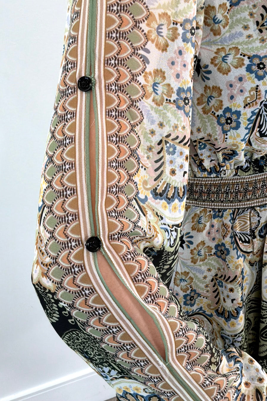 Close-up of an ivory, green and black short A-line long sleeve dress