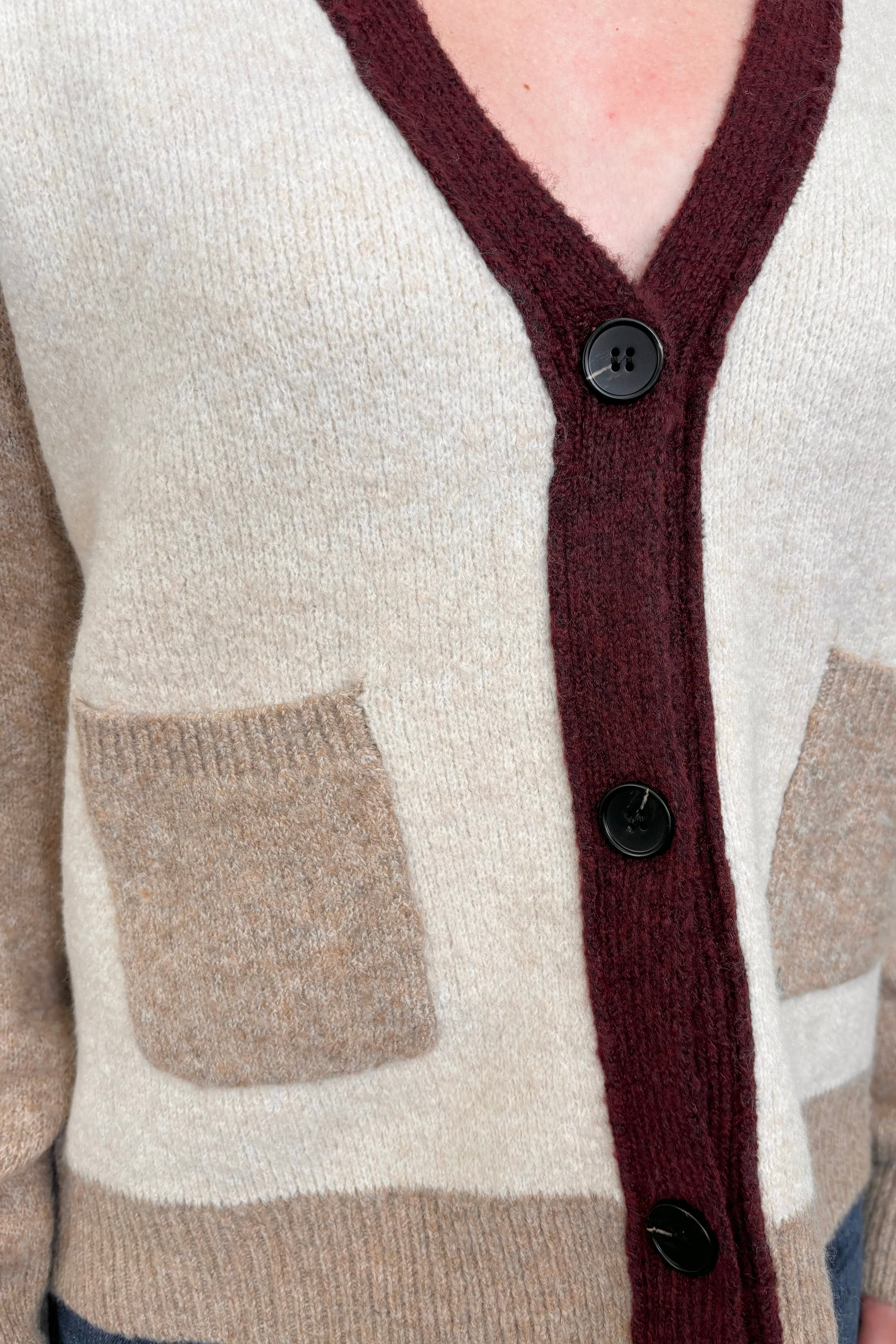 Close up of a colour block beige and burgundy cardigan with pockets