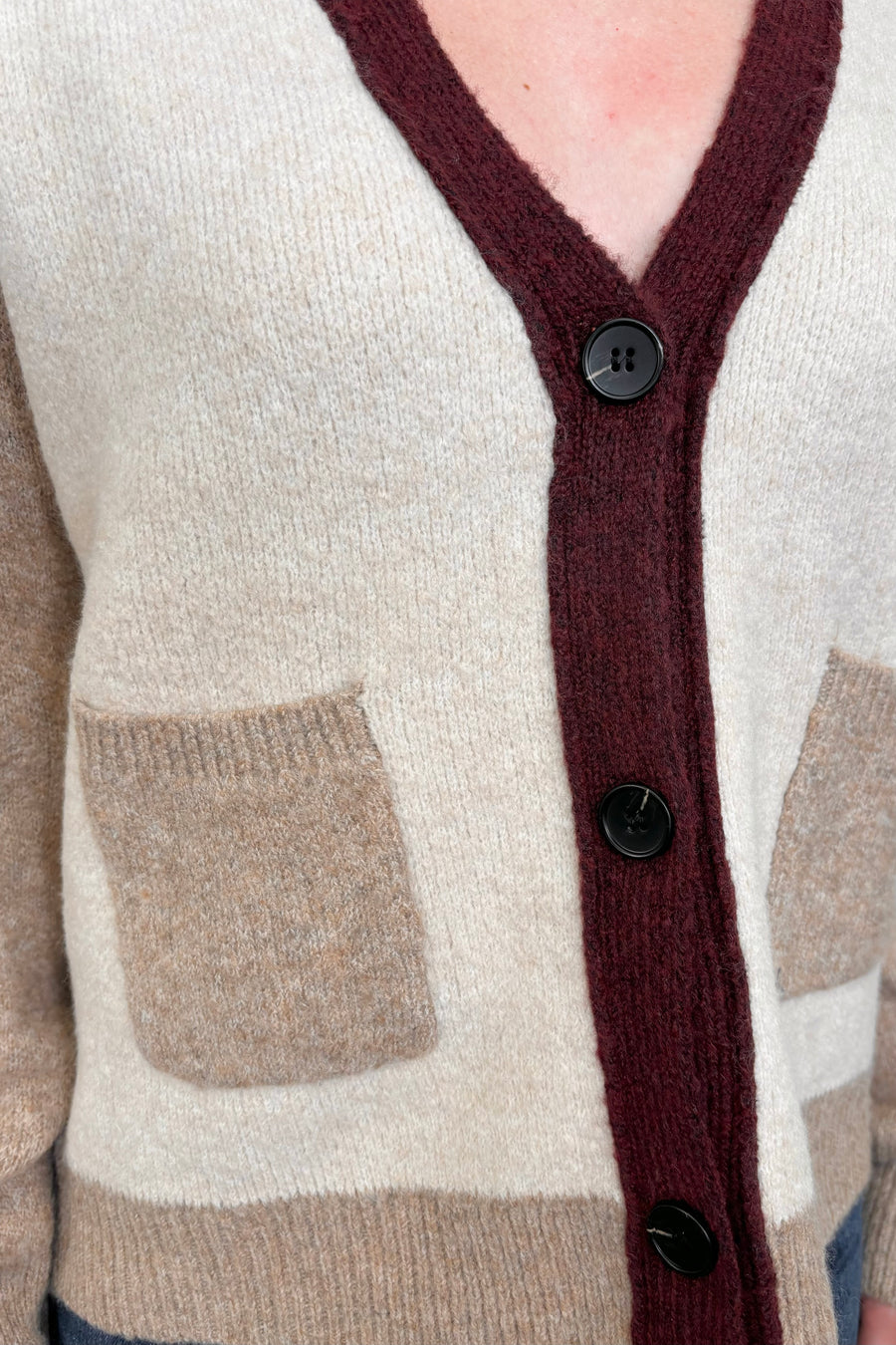 Close up of a colour block beige and burgundy cardigan with pockets