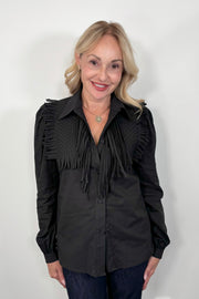 Woman wearing a black long sleeve collared blouse with fringes untucked