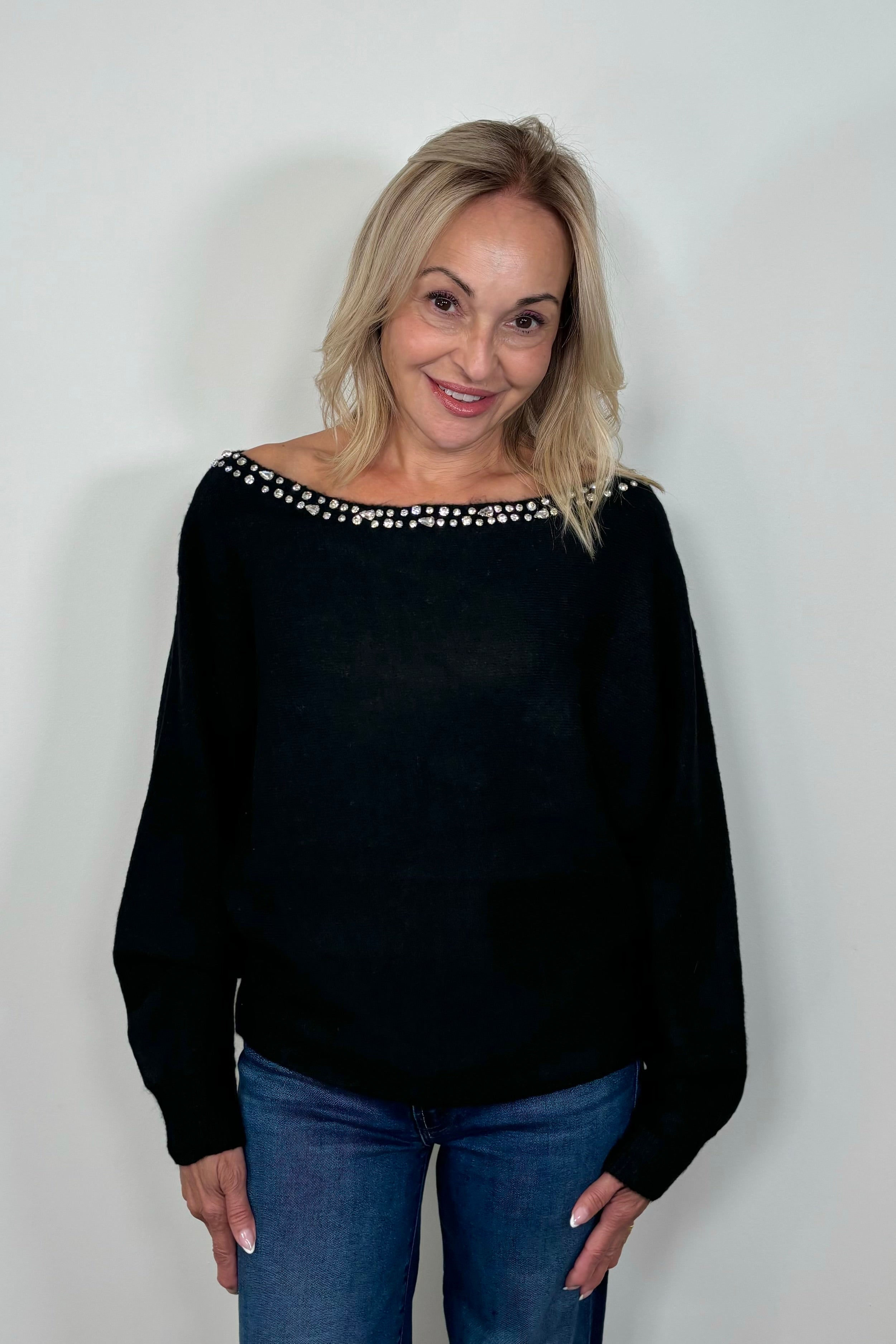 Front view of woman wearing a black sweater with rhinestones in the neckline