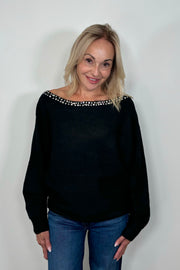 Front view of woman wearing a black sweater with rhinestones in the neckline