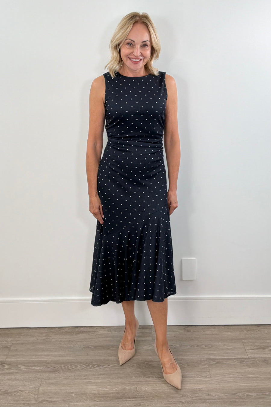 Woman wearing a navy dress with white polka dots
