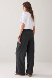 Woman wearing a white t-shirt and black pinstripe pants on a plain background