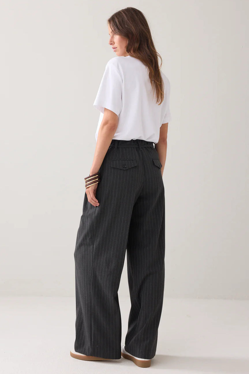Woman wearing a white t-shirt and black pinstripe pants on a plain background