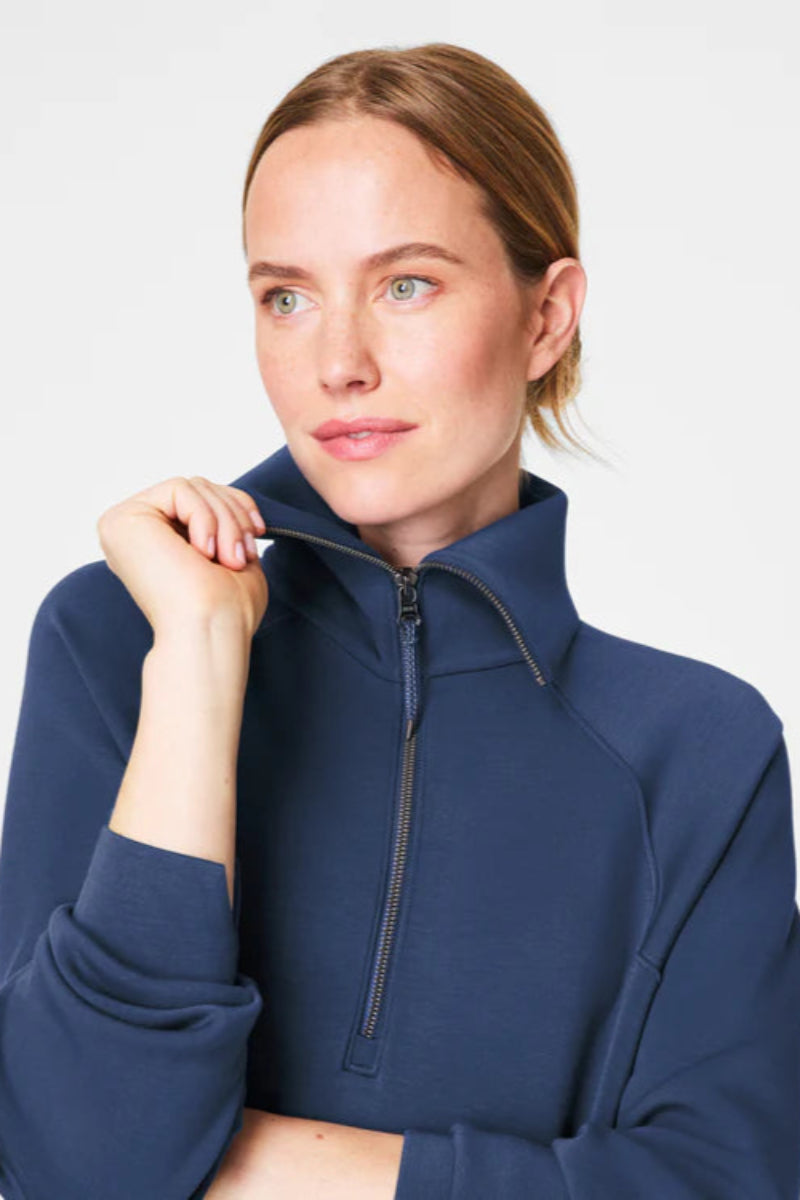 Woman wearing a navy blue zip-up sweatshirt against a light gray background