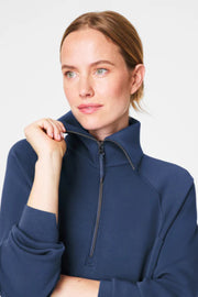 Woman wearing a navy blue zip-up sweatshirt against a light gray background