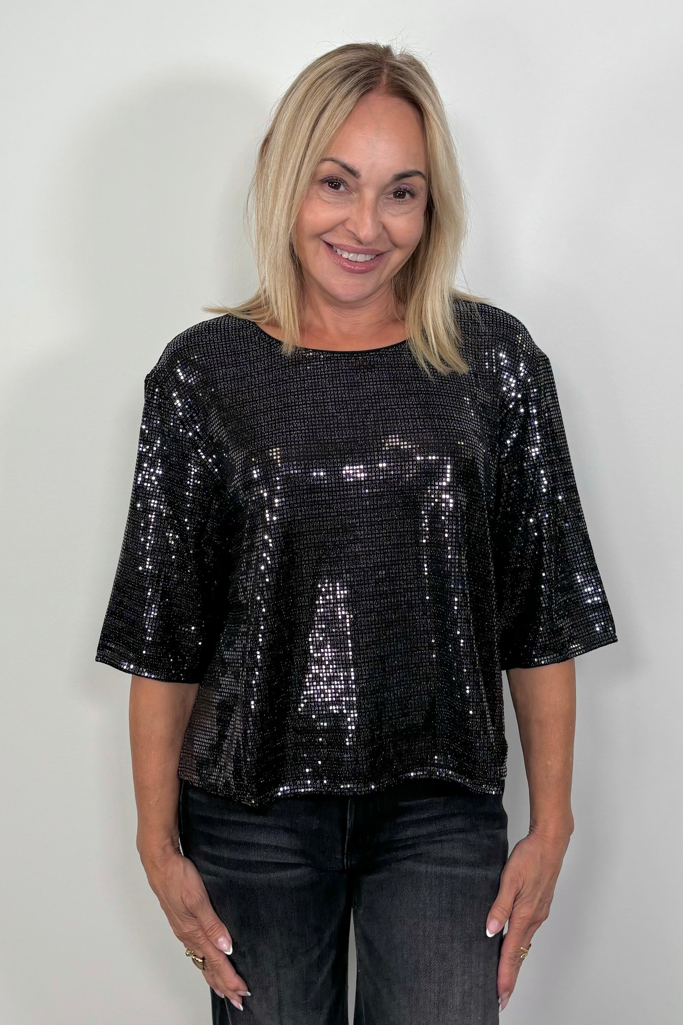 Front view of woman wearing a half sleeve shimmery crew top