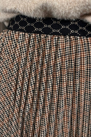 Person wearing a beige sweater and plaid skirt on a light background