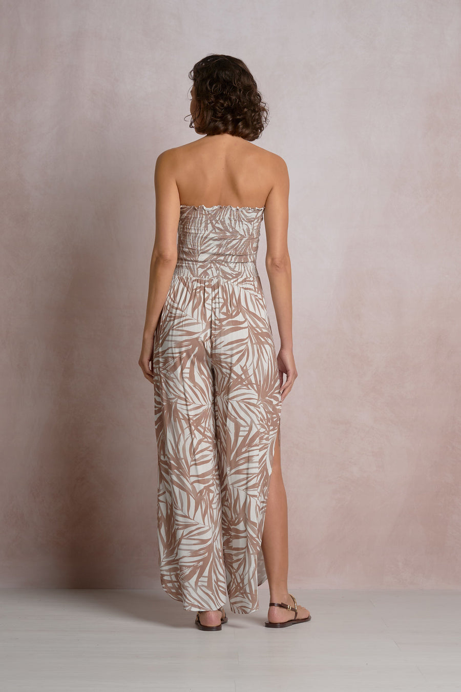 Woman wearing a beige and white strapless dress with a  palm leaf pattern