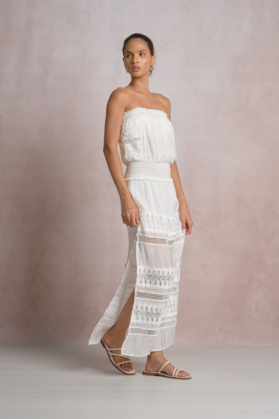 woman wearing a maxi strapless white dress with lace details in the skirt