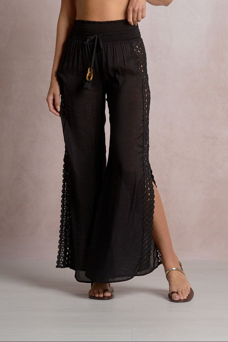 black pants with eyelet detailing on the sides and a slit