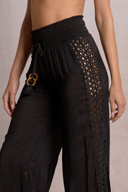 black pants with eyelet detailing on the sides and a slit
