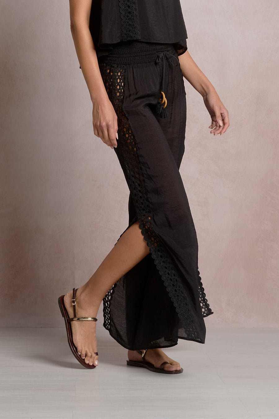 black pants with eyelet detailing on the sides and a slit