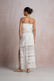 woman wearing a maxi strapless white dress with lace details in the skirt