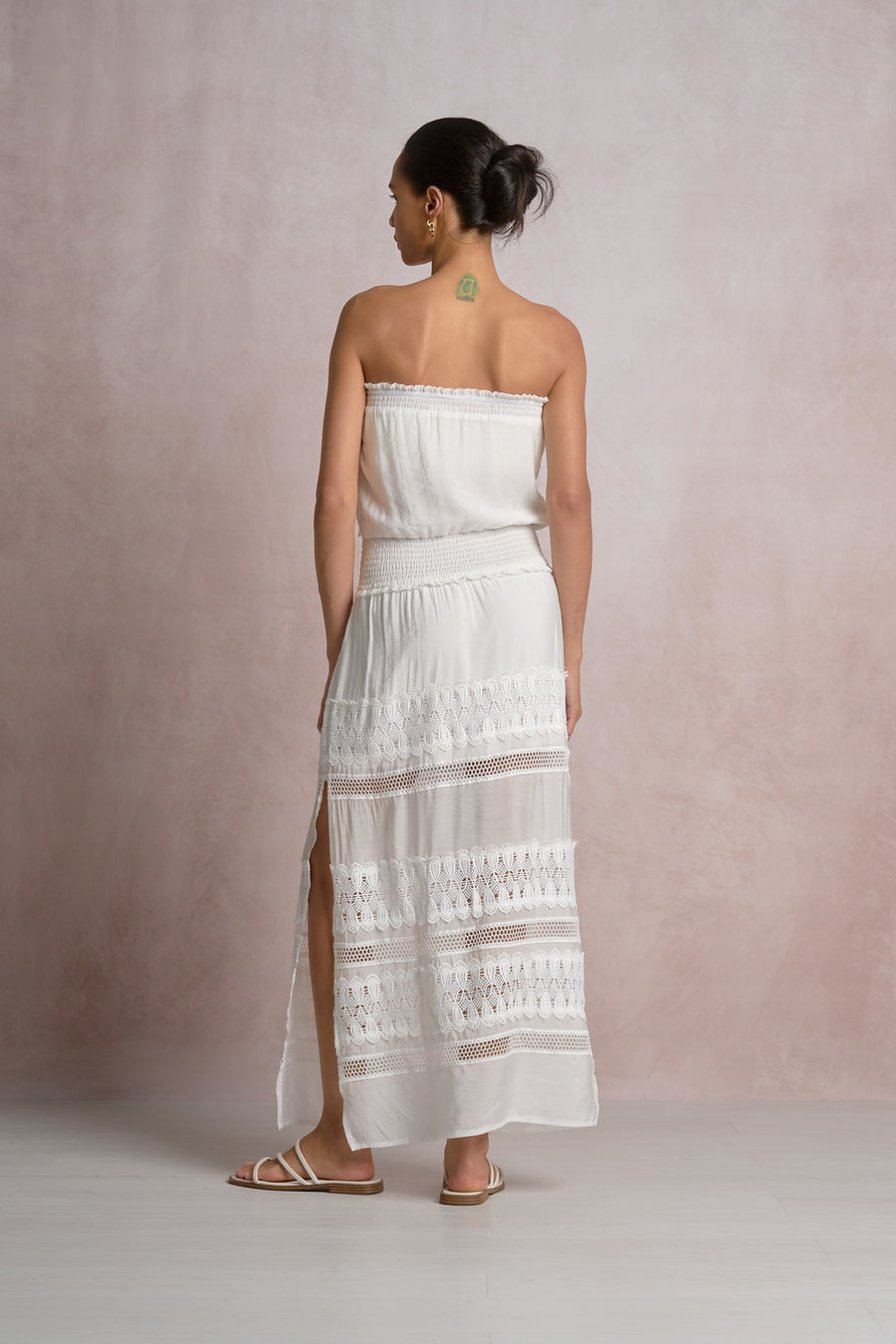 woman wearing a maxi strapless white dress with lace details in the skirt