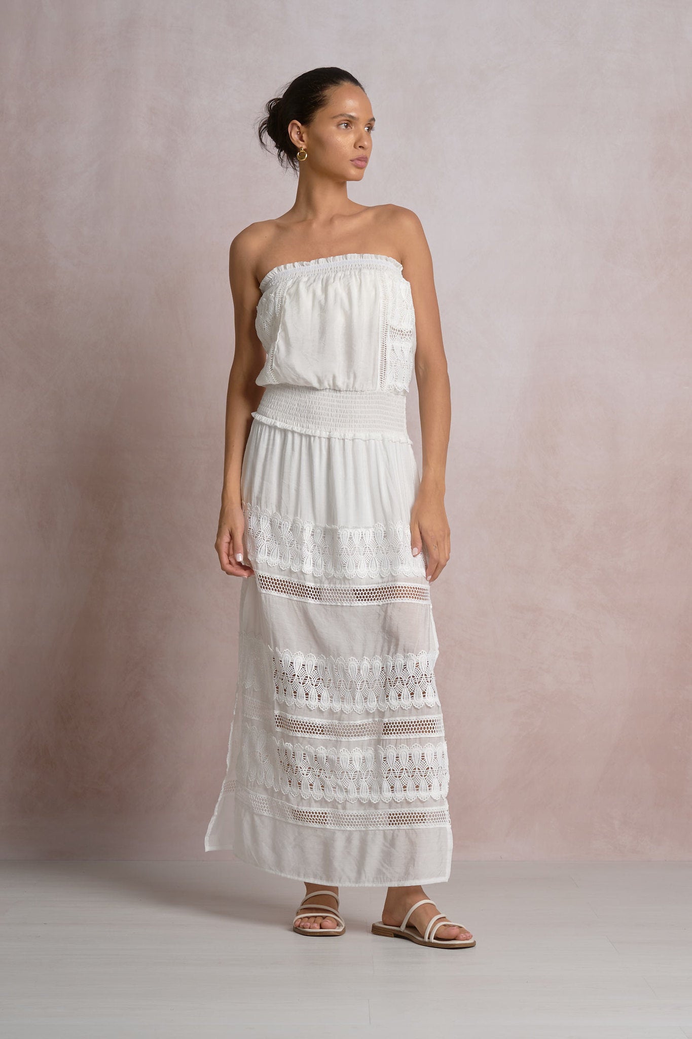 woman wearing a maxi strapless white dress with lace details in the skirt