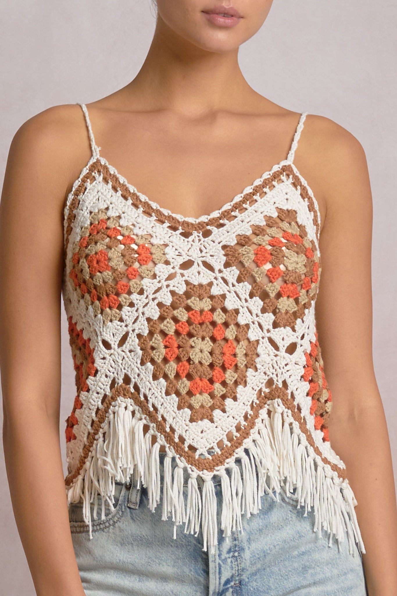 close-up of a white, beige, orange and brown crochet frayed tank top