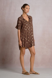 woman wearing a brown short shirt dress with gold detailing