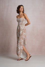 Woman wearing a beige and white strapless dress with a  palm leaf pattern