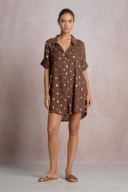 woman wearing a brown short shirt dress with gold detailing