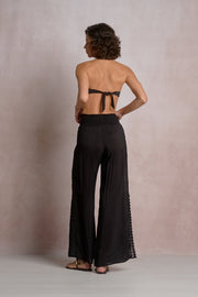 black pants with eyelet detailing on the sides and a slit