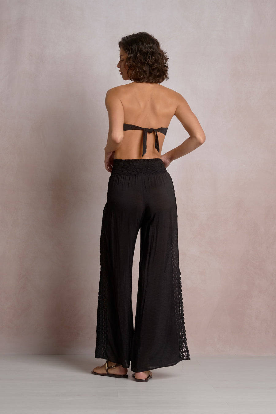 black pants with eyelet detailing on the sides and a slit