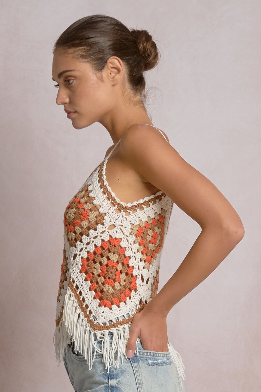 woman wearing a white, beige, orange and brown crochet frayed tank top