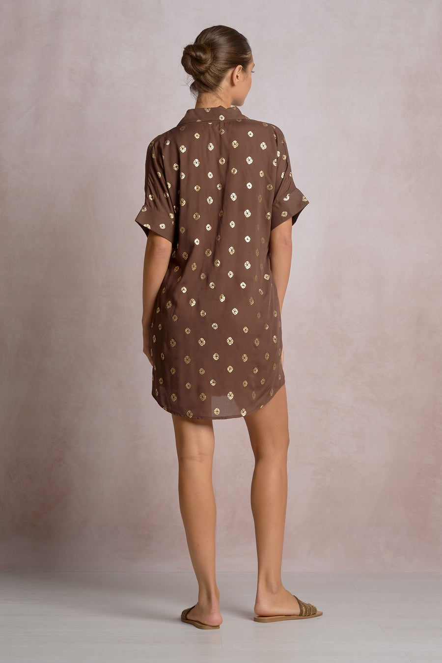 woman wearing a brown short shirt dress with gold detailing